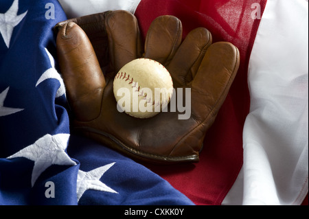 Eine Gruppierung von klassischen Baseball-Elemente einschließlich einer antiken Handschuh oder Mitt und eine antike Baseball oben auf eine amerikanische Flagge Stockfoto