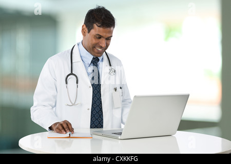 Männlicher indischer Arzt an der Rezeption auf seinem Laptop. Stockfoto