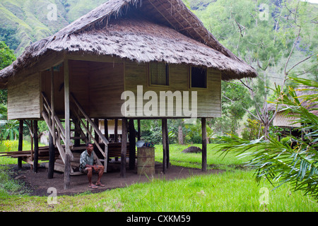 Mann, sitzend durch ein Dorfhaus in Erap Valley, Papua-Neu-Guinea Stockfoto