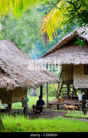 Mann, sitzend durch ein Dorfhaus in Erap Valley, Papua-Neu-Guinea Stockfoto