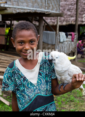 Jungen Dorfmädchen lächelnd und halten ein Triton Kakadu (Cacatua Galerita Triton), Erap Valley, Papua New Guinea Stockfoto