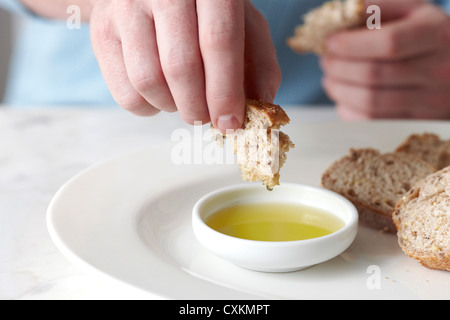 Mann Baguette in Olivenöl getaucht Stockfoto