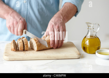 Mann schneiden Baguette Stockfoto