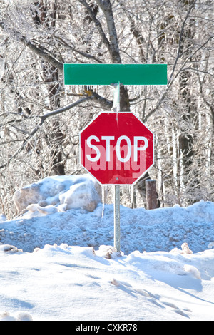 Stop-Schild in der Mitte von einem Snowbank und bedeckt im Eis und Eiszapfen. Stockfoto