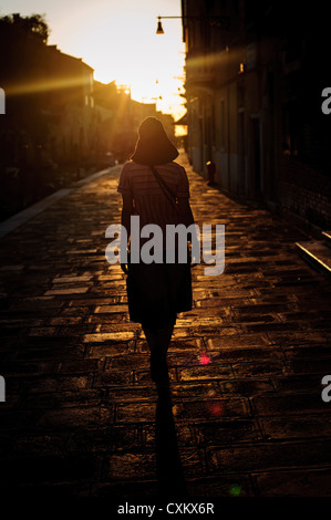 Eine Frau mit einem Hut zu Fuß in die Cannargeio während der Zeit des Sonnenuntergangs, Venedig, Italien. Stockfoto