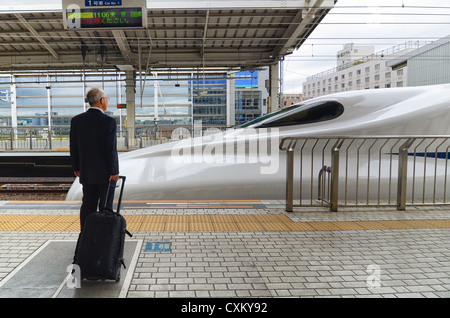 Ein Passagier wartet auf einem Bahnsteig, während ein Bullet-Zug kommt. Stockfoto