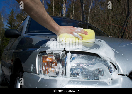 Mann Waschen Auto an einem sonnigen Tag mit einem Schwamm. Stockfoto