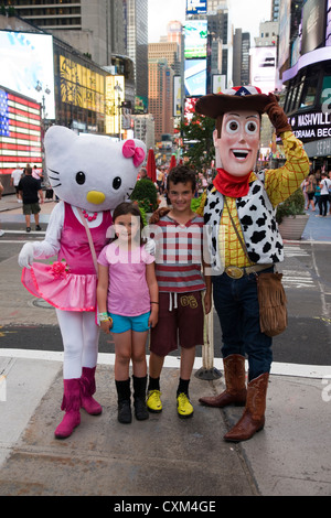 Kinder posieren für ein Foto mit Comic-Figuren Hello Kitty und Woody von Toy Story am Times Square, New York Stockfoto