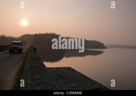 Schönen Abend Licht bei Sonnenuntergang über dem ruhigen Wasser des ländlichen, ruhigen malerischen See & Auto fahren - Thruscross Reservoir, North Yorkshire, England, UK. Stockfoto