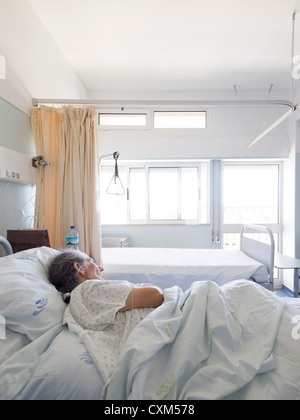 Ältere Frau liegt auf ihrem Bett in einer Krankenstation Stockfoto