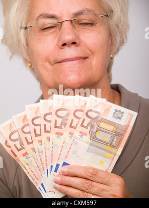 Happy mature woman holding money (euro bills) Stockfoto