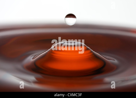 ein Wassertropfen in einen Spritzer rot ausgesetzt Stockfoto