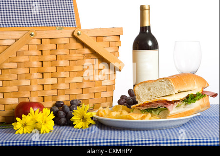 Ein Picknick-Mittagessen, bestehend aus einem Sandwich, Kartoffelchips und Trauben auf einem blau karierte oder aufgegebenes Tischdecke Stockfoto