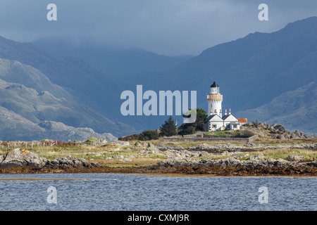 Alte traditionelle Leuchtturm auf der Insel Ornsay auf Skye mit Bergen auf dem schottischen Festland über. Stockfoto