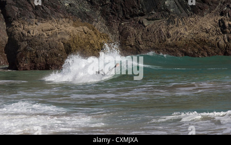 Ein Boarder oder Short Boarder in der Brandung in Kynance Cove auf der Lizard Peninsula, Cornwall, England Stockfoto