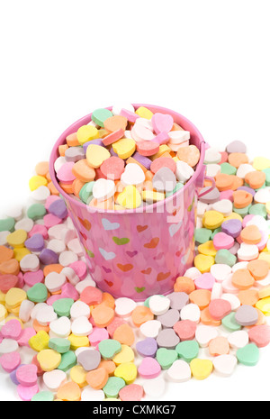 Ein rosa Eimer überfüllt mit Valentinstag Süßigkeiten, Gespräch Herzen auf weißem Hintergrund Stockfoto