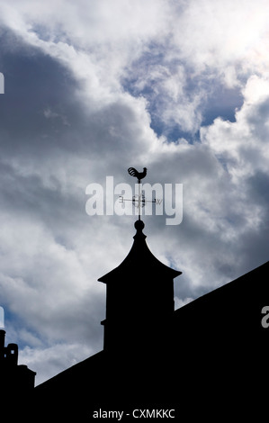 Eine Wetterfahne auf einem Turm ist gegen ein bewölkter Himmel abhebt. Stockfoto