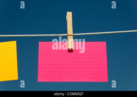 leere rosa Karteikarte auf einer Wäscheleine mit blauem Himmelshintergrund Stockfoto