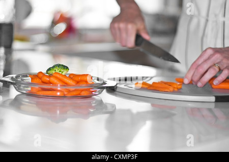 Frau schneiden Möhren auf Küche Zähler board Stockfoto