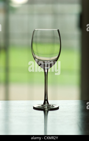 Sehr geringe Schärfentiefe Feld Bild von einem einzigen leeren Weinglas auf einem Tisch Stockfoto