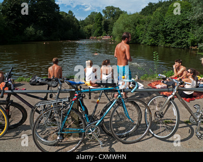 Badegäste Schwimmer und Fahrräder im Hampstead Heath gemischten Badeteich an einem heißen Tag im Sommer North London NW3 England UK KATHY DEWITT Stockfoto