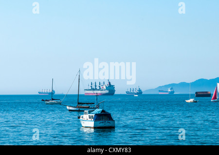 An einem trüben Tag warten private Boote und Handelsschiffe in der English Bay außerhalb von Vancouver, BC. Vom Vanier Park aus gesehen. Stockfoto