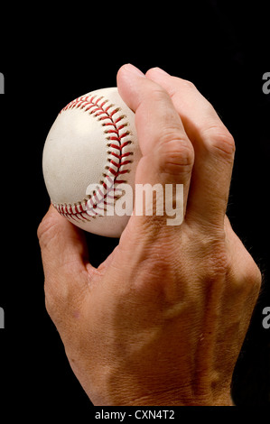 Mannes Hand hält einen Baseball in einem pitching Griff auf schwarzem Hintergrund Stockfoto