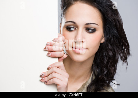 Portrait über eine attraktive junge Brünette mit leeren weißen Schild. Stockfoto