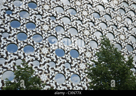 Moderne architektonische Verkleidung mit ineinandergreifenden metallischen Formen bildet interessante Muster und Hintergrund mit Rundfenster Stockfoto