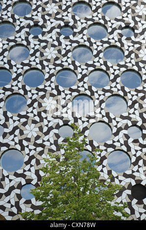 Moderne architektonische Verkleidung mit ineinandergreifenden metallischen Formen bildet interessante Muster und Hintergrund mit Rundfenster Stockfoto