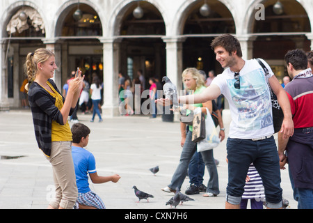 Junge Paare, die Fotos machen und Tauben füttern auf dem Markusplatz Venedig Italien Stockfoto