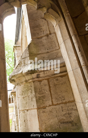 zerkratzte Namen von ehemaligen Schülern auf dem Stein rund um den Kreuzgang des Winchester college Stockfoto