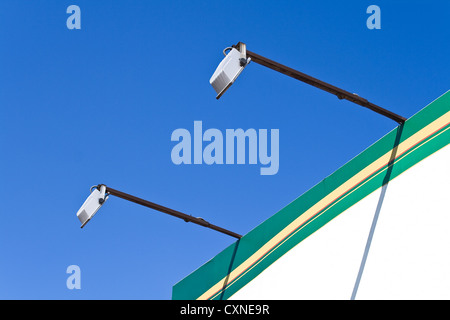 Zwei Scheinwerfer Pole auf Plakatwand über blauen Himmel Stockfoto