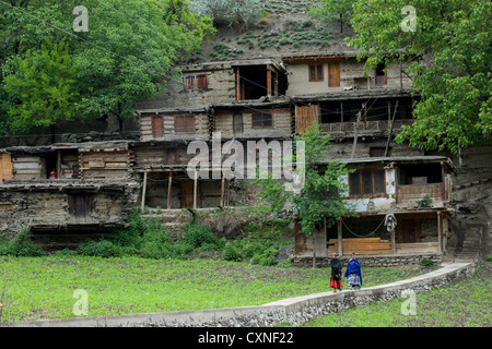 Kalash Frauen vorbei an steil terrassierte Häuser im Dorf Kalasha Grum, Rumbur Tal, Chitral, Khyber-Pakhtunkhwa, Pakistan Stockfoto