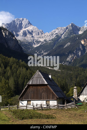 Traditionelles Trenta Steinhaus mit Holzdach und externem Kamin mit Berghintergrund. Stockfoto