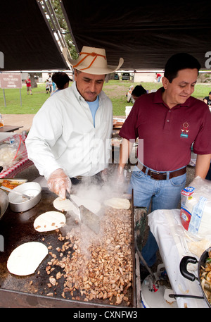 Hispanische männliche Männer neigen dazu, auf outdoor-Food-Stand auf der Kirche Festival in Austin / Texas grill Stockfoto