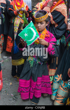 Kalash junge Mädchen in traditioneller Kleidung hält eine Pakistan-Fahne am Anish Brun Dorf Charso (tanzen Boden), Kalash Joshi (Frühlingsfest), Bumburet Tal, Chitral, Khyber-Pakhtunkhwa, Pakistan Stockfoto