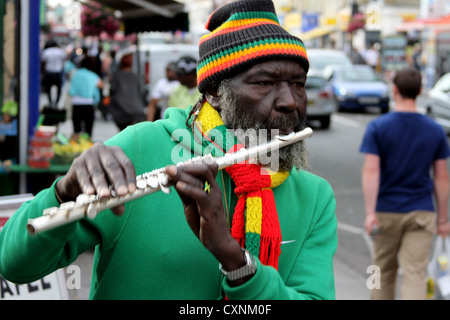 Afrikanischer Flötenspieler auf der Straße kaukasischer Mann, der hinter sich herläuft Stockfoto