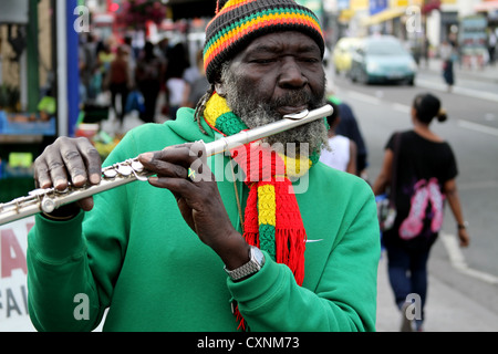 Afrikanischer Flötenspieler auf der Straße afrikanisches Mädchen, das hinter sich geht Stockfoto