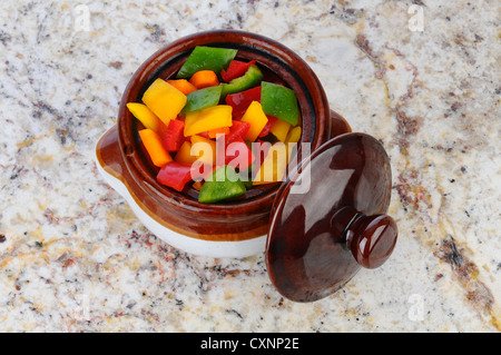 Ein Topf Schüssel voller Frische gewürfelte grün, rot, gelb und Orange Paprika. Draufsicht auf eine Granit-Arbeitsplatte. Stockfoto