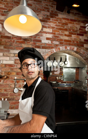 Pizza Chef steht in der Küche in einem Pizza Restaurant machen Teig beim Anhören von Kundenaufträge Stockfoto