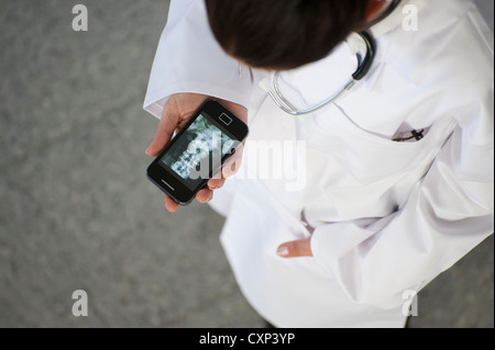 Ärztin, Blick auf Röntgenbild auf smartphone Stockfoto