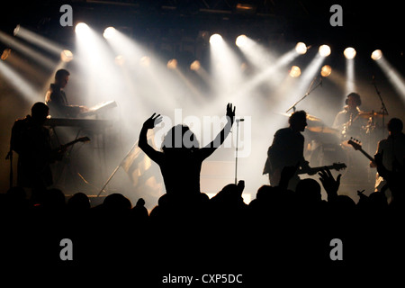 Silhouetted Zuschauer/Masse und Ambiente während live Rock Konzert mit Rocker auf der Bühne durch Strahler beleuchtet Stockfoto