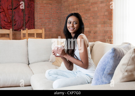 Glückliche Frau in ihre Lounge mit Kaffee Stockfoto