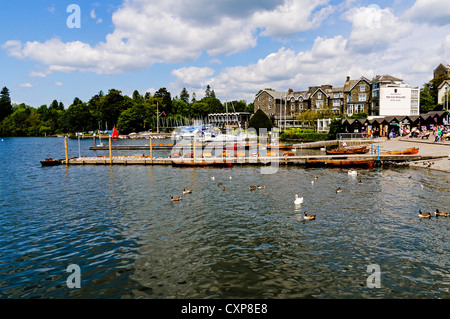 Touristen entspannen auf der Uferstraße in Bowness mit Blick auf Ruderboote zu mieten am malerischen Lake Windermere Stockfoto