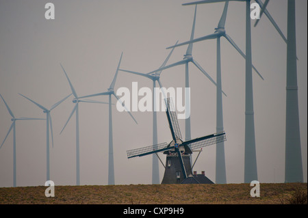 Eine alte holländische Windmühle ist vor dem Hintergrund einer Reihe von modernen Windkraftanlagen in Friesland im Norden der Niederlande gesehen. Stockfoto