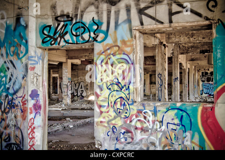Innenraum einer verlassenen Fabrik. Das Betonskelett des Gebäudes bedeckt Graffiti in Detroit Michigan. Stockfoto