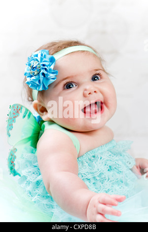 6 Monate altes Baby Mädchen tragen Türkis geraffte Pumphose und Feenflügel schlägt eine glückliche Pose. Stockfoto