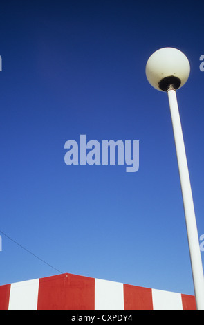 Spitze des Gebäudes gemalt mit breiten roten und weißen Bändern mit Telefon Draht und Globe Straßenlaterne unter blauem Himmel Stockfoto