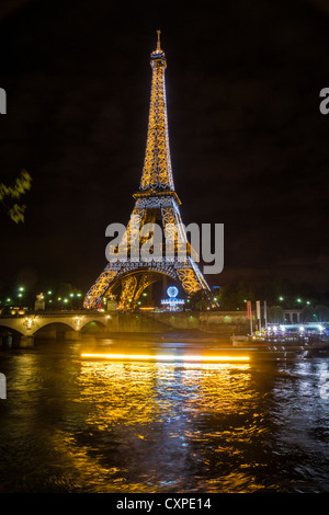 Paris. Der Eiffelturm bei Nacht, hoch über dem Fluss Seine. Boote und Fähren auf der unteren Hälfte des Bildes zu sehen Stockfoto